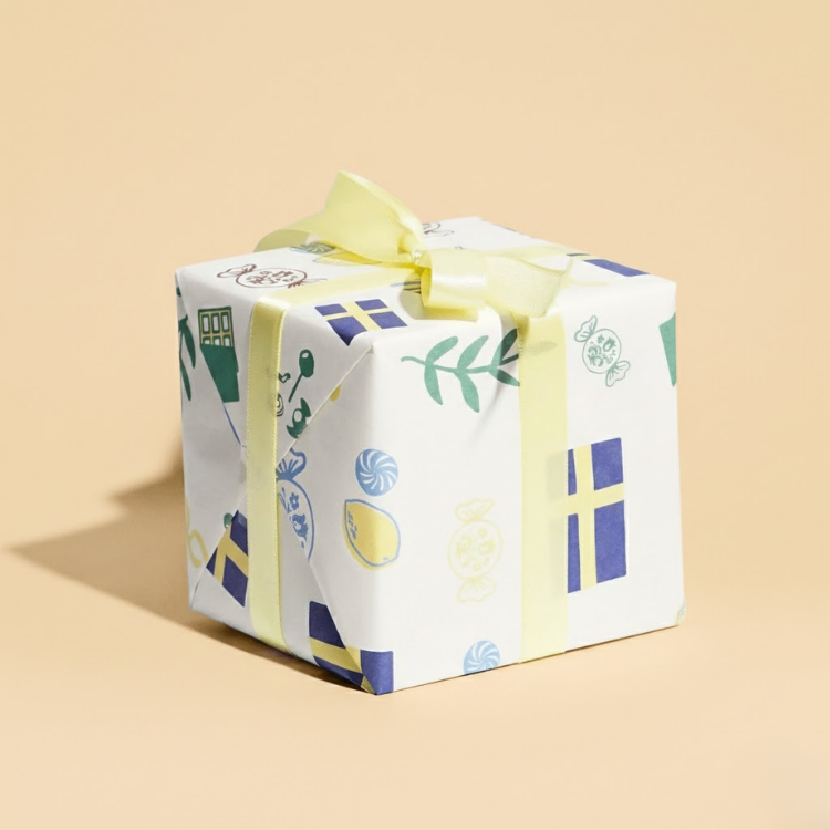 lilla swedish candy box wrapped in colorful paper with a yellow ribbon on a beige background