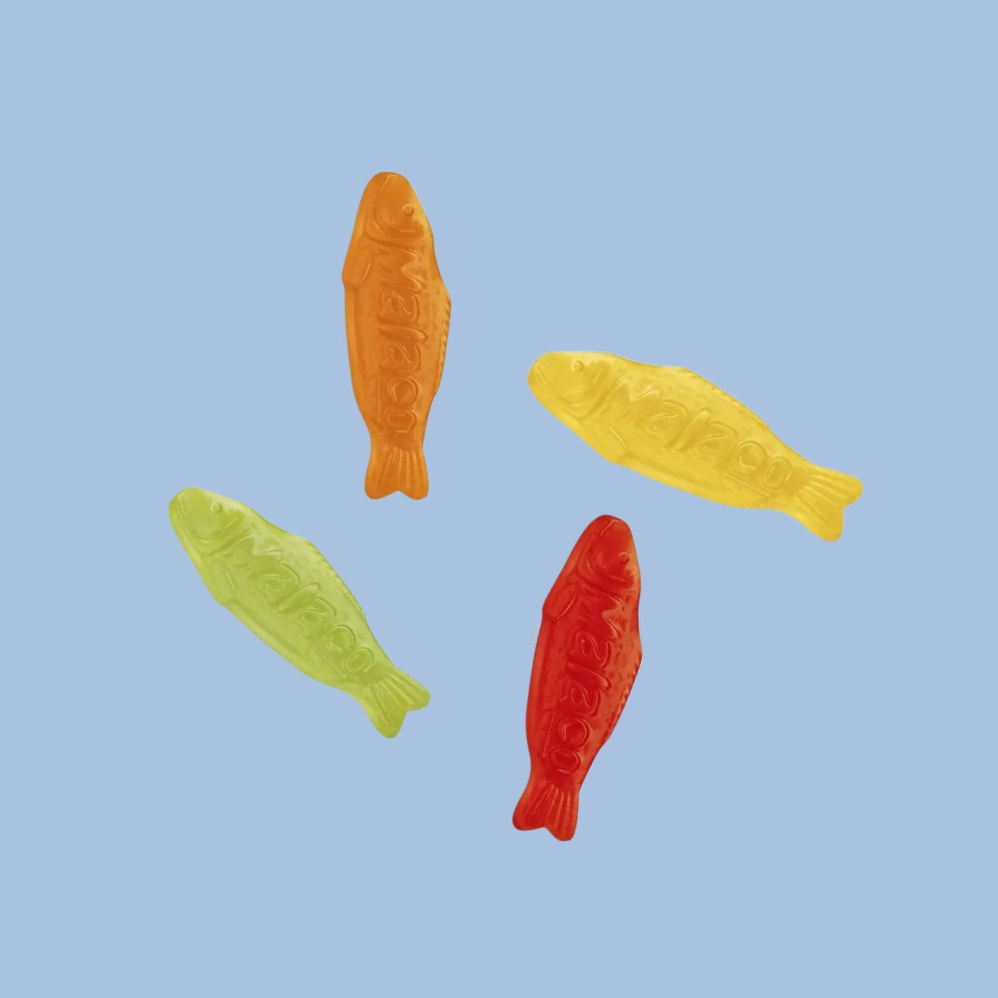 Four fish-shaped gummy candies in red, yellow, green, and orange on a light blue background.