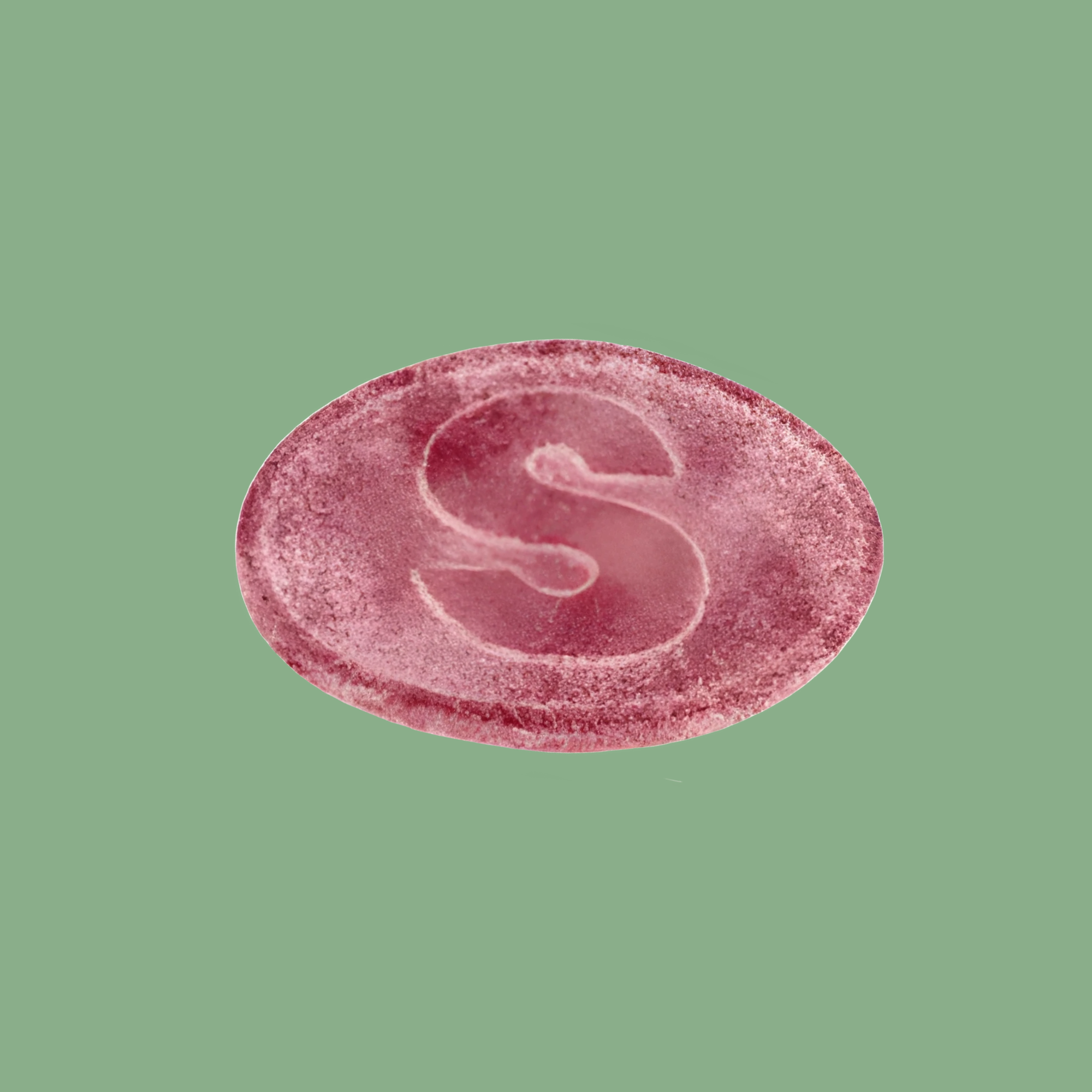 Pink circular object with a letter 'S' on a green background